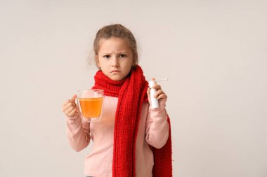 Limon çayıyla hasta küçük bir kız ve hafif arka planda boğaz ağrısı için sprey