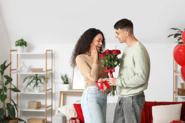Genç adam evde gül buketiyle kız arkadaşına sürpriz yapıyor. Sevgililer Günü kutlaması