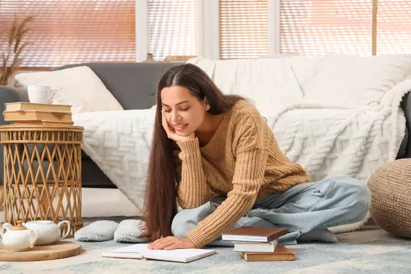 Güzel, genç, mutlu bir kadın evde kitap okuyor.