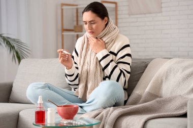 Evdeki masada termometresi ve çorbası olan hasta genç bir kadın.