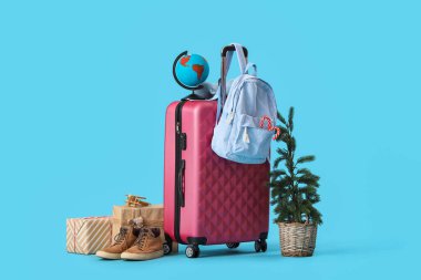 Mavi arka planda Noel ve seyahat dekorlarıyla dolu bavul