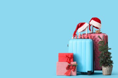 Mavi arka planda Noel ve seyahat aksesuarları olan bavullar