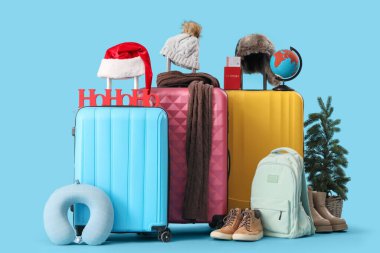 Mavi arka planda kış ve seyahat aksesuarları olan bavullar