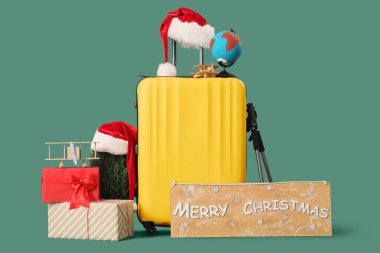 Bavul, üzerinde Merry Christmas yazan tahta ve yeşil arkaplanda aksesuarlar