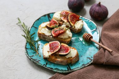 Beyaz arka planda ricotta peynirli ve biberiyeli lezzetli incirli bruschetta tabağı.