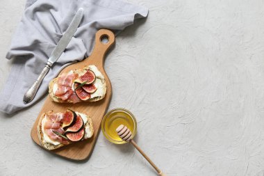 Beyaz arka planda prosciutto ve ricotta peynirli lezzetli incirli bruschetta tahtası.