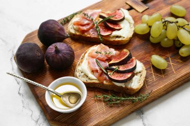 Beyaz arka planda prosciutto ve ricotta peynirli lezzetli incirli bruschetta tahtası.