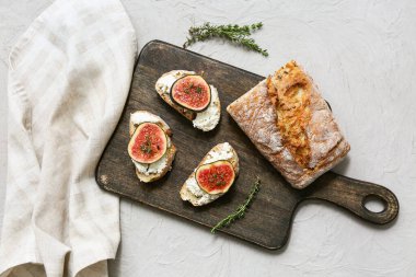 Beyaz arka planda ricotta peynirli lezzetli incirli bruschetta tahtası.