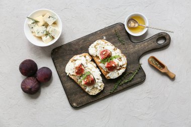 Beyaz arka planda ricotta peyniri ve roka ile lezzetli incir bruschetta tahtası.