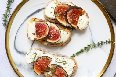 Beyaz arka planda ricotta peynirli lezzetli incirli bruschetta tabağı.