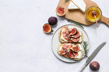 Beyaz arka planda prosciutto ve ricotta peynirli lezzetli incirli bruschetta tabağı.