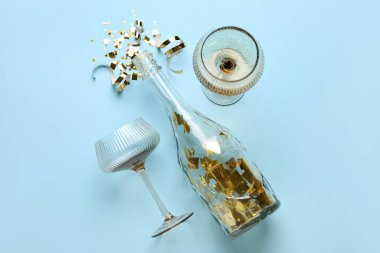 Şampanya şişesi ve mavi arka planda konfeti olan bardaklar. Yeni yıl kutlaması