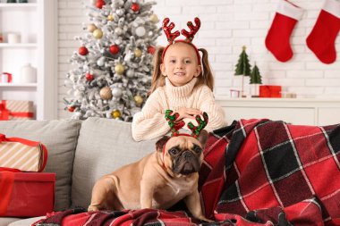 Sevimli küçük kız ve evde saç bandı takan Fransız bulldog.