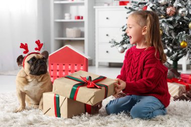 Evde Fransız bulldog 'u ve Noel hediyeleriyle sevimli küçük bir kız.