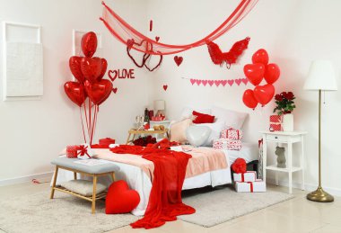 Interior of light bedroom decorated for Valentine's Day with bed, presents and balloons clipart