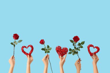 Mavi arka planda gülleri ve kalpleri olan kadın elleri. Sevgililer Günü kutlaması