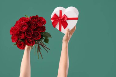Yeşil arka planda gül ve hediye kutusu olan kadın elleri. Sevgililer Günü kutlaması