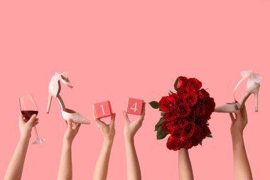 Pembe arka planda gül, ayakkabı, şarap ve küp takvimi olan kadın elleri. Sevgililer Günü kutlaması