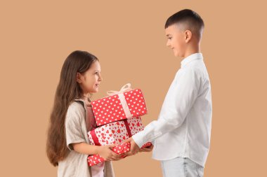 Bej arka planda hediye kutuları olan şirin çocuklar. Sevgililer Günü kutlaması