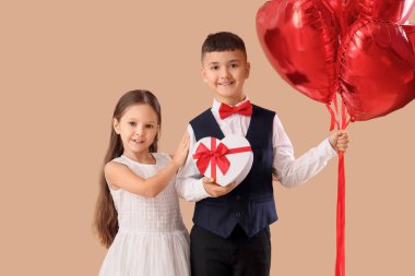 Kalp şeklinde balonları ve bej arka planda hediye kutusu olan şirin çocuklar. Sevgililer Günü kutlaması
