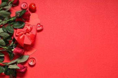 Güzel gül çiçekleri, hediye kutusu ve kırmızı arka plandaki Sevgililer Günü kutlaması için yanan mumlar.