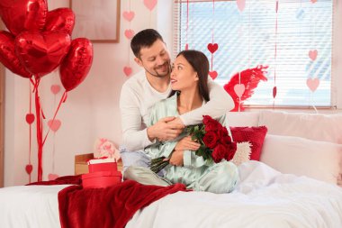 Sevgililer Günü 'nde karısını güllerle kucaklayan genç bir adam.