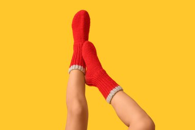 Sarı arka planda kırmızı örgü çoraplı genç bir kadın.