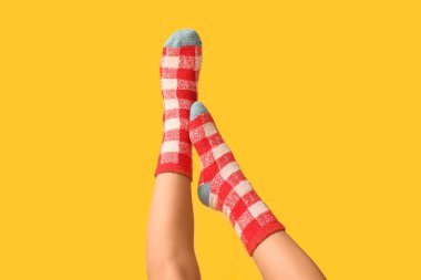 Sarı arka planda sıcak kareli çoraplı genç kadın bacakları.