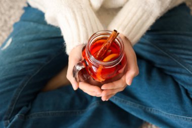 Kadın elinde sıcak şarap kavanozu tutuyor, yakın plan.