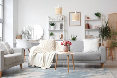 Gri koltukları, raf üniteleri ve bitkileri olan şık bir oturma odası.