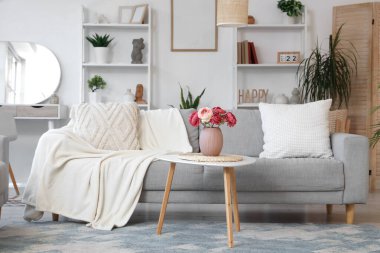 Gri kanepe ve vazoda şakayık çiçekleri olan şık bir oturma odası.