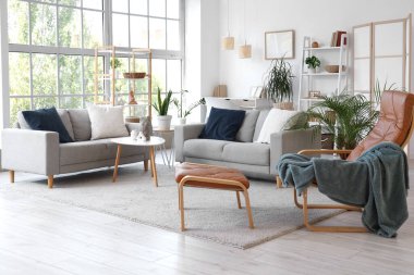 Gri koltukları, koltuğu ve bitkileri olan oturma odasının içinde.