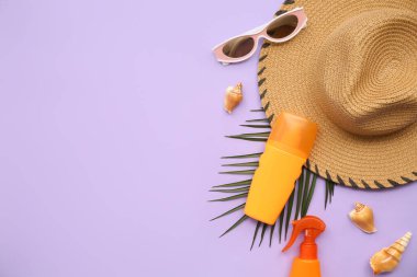 Güneş kremi, güneş gözlüğü, şapka ve arka planda palmiye yaprağı olan kompozisyon