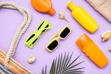 Leylak arka planında güneş kremi, çanta ve güneş gözlüğü olan kompozisyon