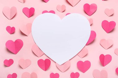 Pembe zemin üzerinde kağıt kalpler olan kompozisyon. Sevgililer Günü.