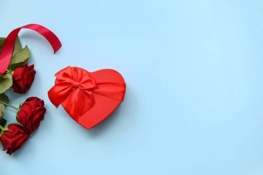 Kalp şeklinde hediye kutusu ve Sevgililer Günü kutlamaları için kırmızı gül çiçekleri.