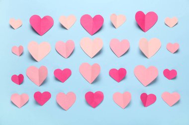Açık mavi zemin üzerinde farklı kağıt kalpler olan kompozisyon. Sevgililer Günü kutlaması