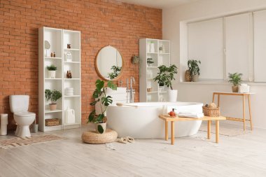 Küvetli, çiçekli ve ahşap banklı şık bir banyo.