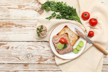 Hafif ahşap zemin üzerinde lezzetli et, tost, domates, maydanoz ve soğan halkaları tabağı.