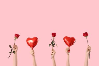 Kalp şeklinde balonlar ve pembe arka planda kırmızı güller tutan kadın elleri. Sevgililer Günü kutlaması