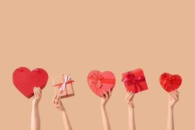 Bej arka planda farklı hediye kutularını tutan kadın elleri. Sevgililer Günü kutlaması