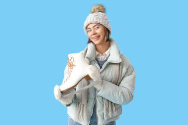 Mavi arka planda buz pateni yapan kışlık elbiseli genç bir kadın.