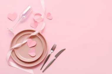 Sevgililer Günü için masa ayarları, pembe arka planda ipek kurdele ve kağıt kalplerle.