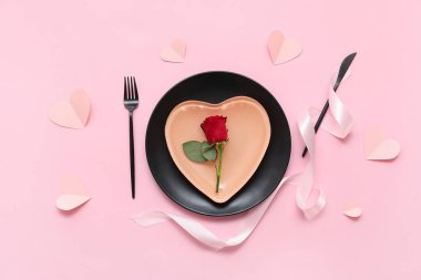 Kağıt kalpli, gül çiçekli ve pembe arkaplanda kurdeleli Sevgililer Günü için masa ayarı