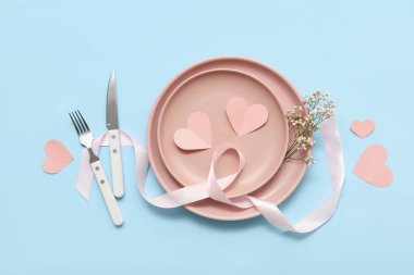 Mavi arka planda beyaz çiçekler, kurdele ve kağıt kalplerle Sevgililer Günü için masa ayarı