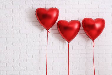 Beyaz tuğla zemin üzerinde kalp şeklinde hava balonları. Sevgililer Günü kutlaması
