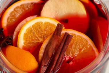 Elmalı, portakallı ve beyaz arka planda farklı baharatlı sıcak sıcak şarap demliği, yakın plan.