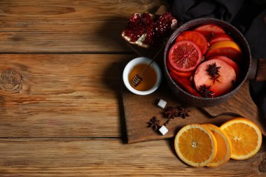 Ahşap zemin üzerinde portakal ve nar ile sıcak sıcak sıcak şarap tenceresi