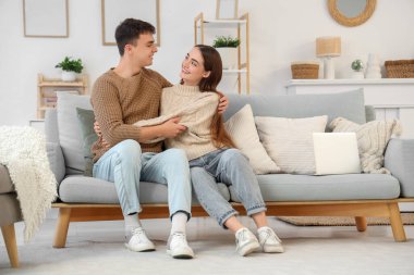 Sevgi dolu genç bir çift evdeki koltukta oturuyor.