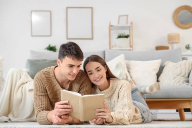 Sevgi dolu genç bir çift evde kitap okuyor.